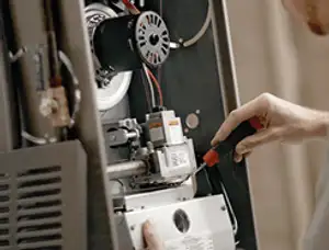 Furnace repair technician inspecting internal components and wiring in Peoria, IL