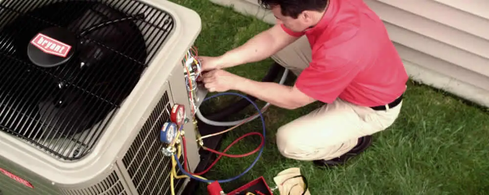 HVAC technician servicing an outdoor air conditioner unit in Peoria, IL