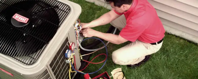 HVAC technician servicing an outdoor air conditioner unit in Peoria, IL