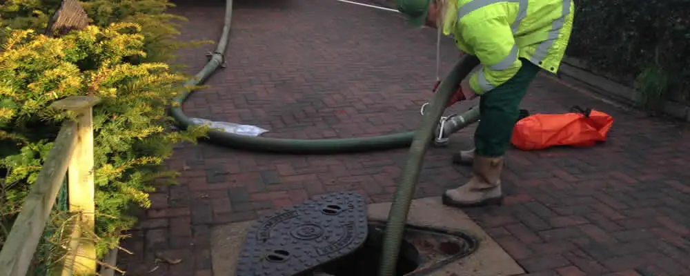 Septic tank cleaning technician servicing a septic tank with a vacuum hose in Peoria, IL