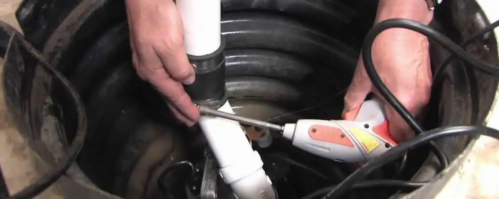 Sump pump installation technician connecting PVC discharge piping in Peoria, IL