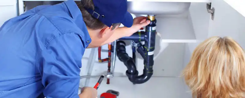 Plumber repairing under-sink drain pipes and fittings in Peoria, IL
